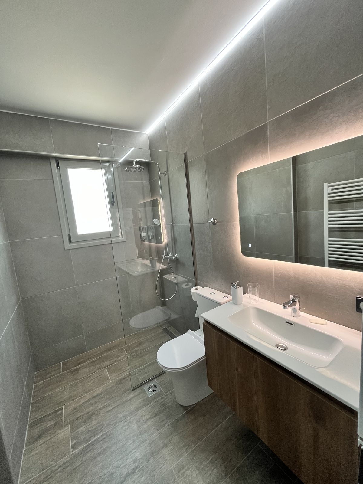 The bathroom, with a walk-in rain shower and LED-lit stone-tiled walls.