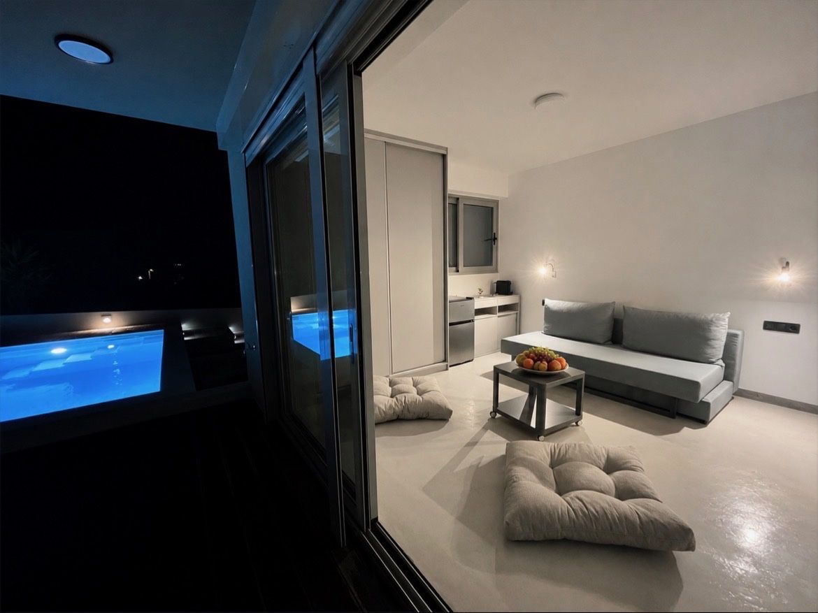 The second bedroom at dusk, with a sofa bed facing the lit pool outside.