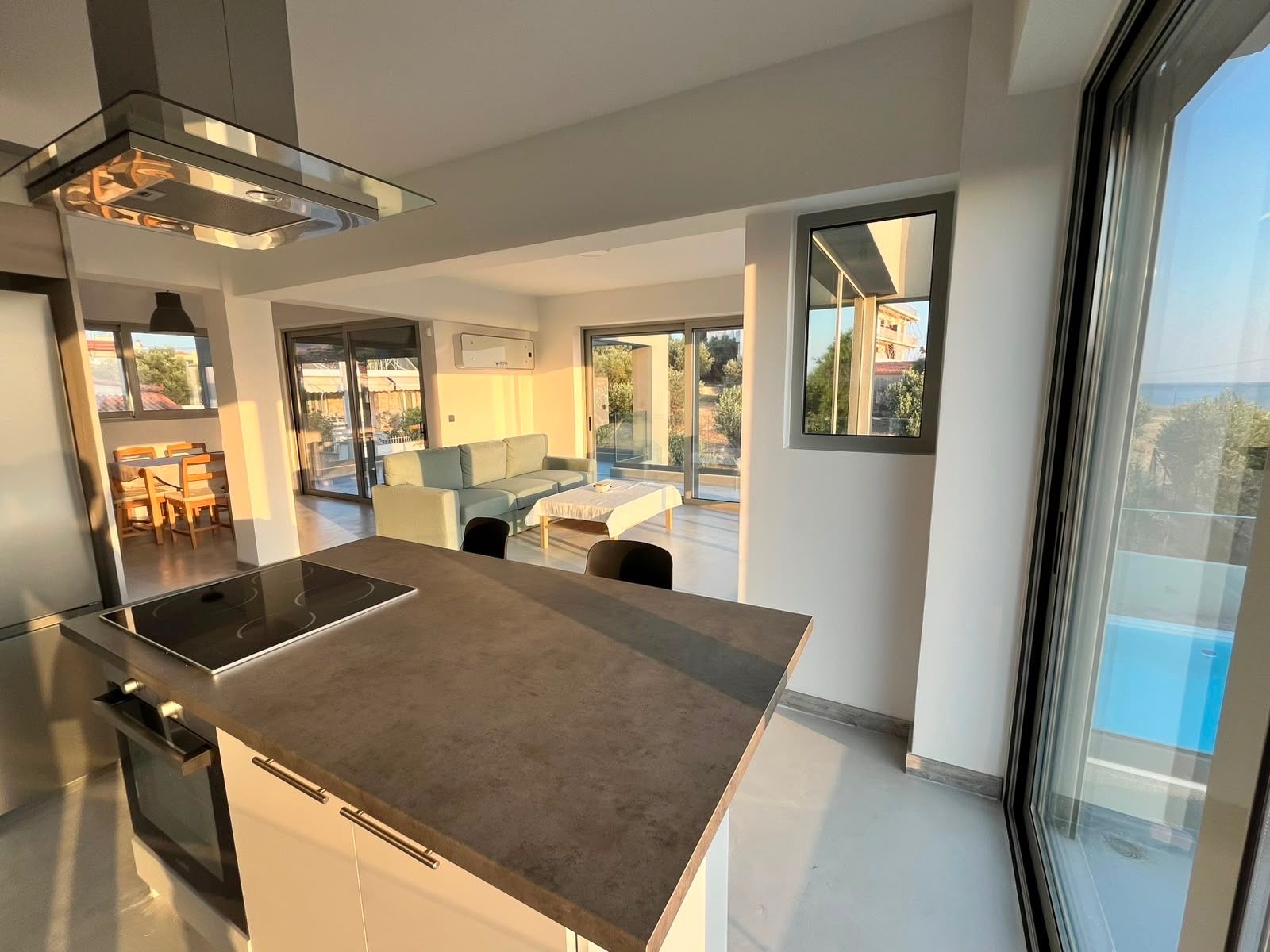 The kitchen island with induction hob, looking through the glass to the sea.
