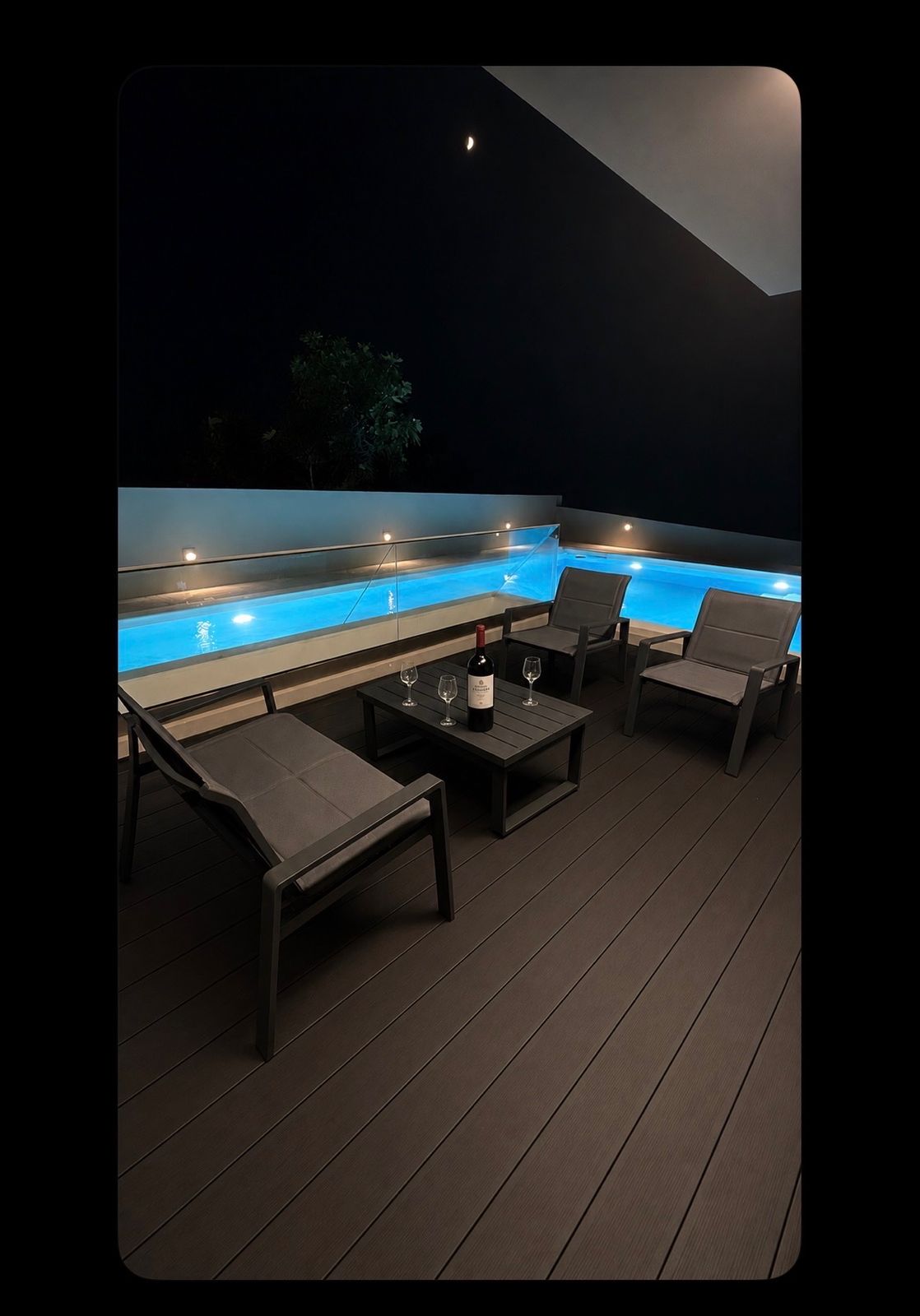 The deck at night, with seating gathered beside the glowing pool.