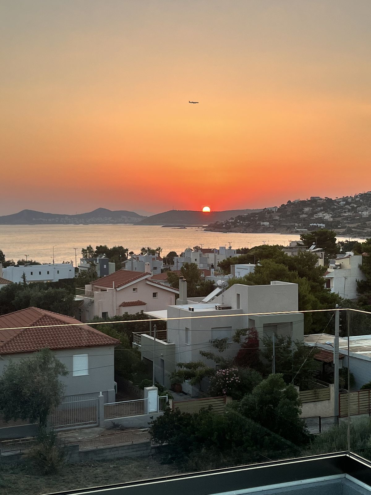 Sunset over the Saronic Gulf from the apartment, the bay fading to orange.