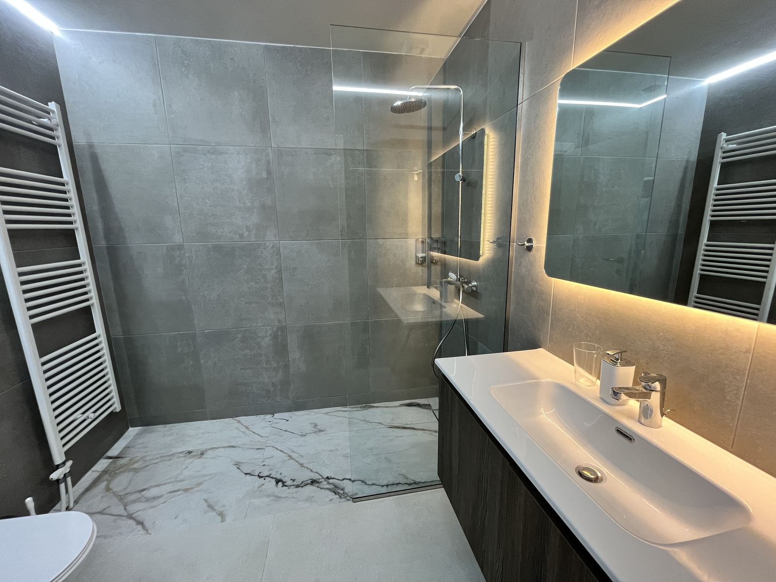 The bathroom, with a walk-in rain shower, heated towel rail and backlit mirror.