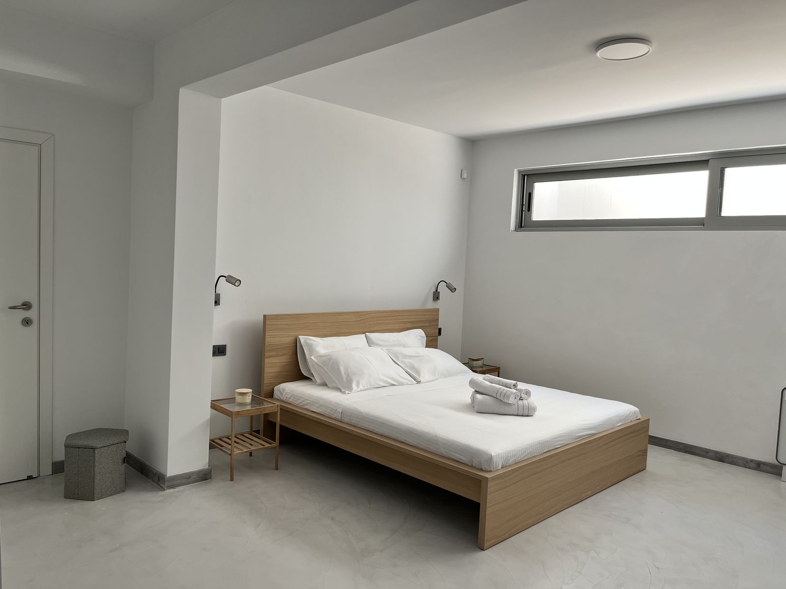 The master bedroom, with a wood-framed double bed and crisp white linens.