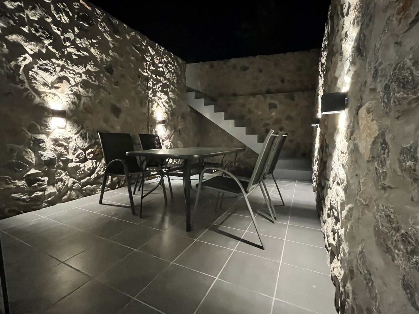 The stone-walled courtyard lit for the evening, with steps rising to the pool.