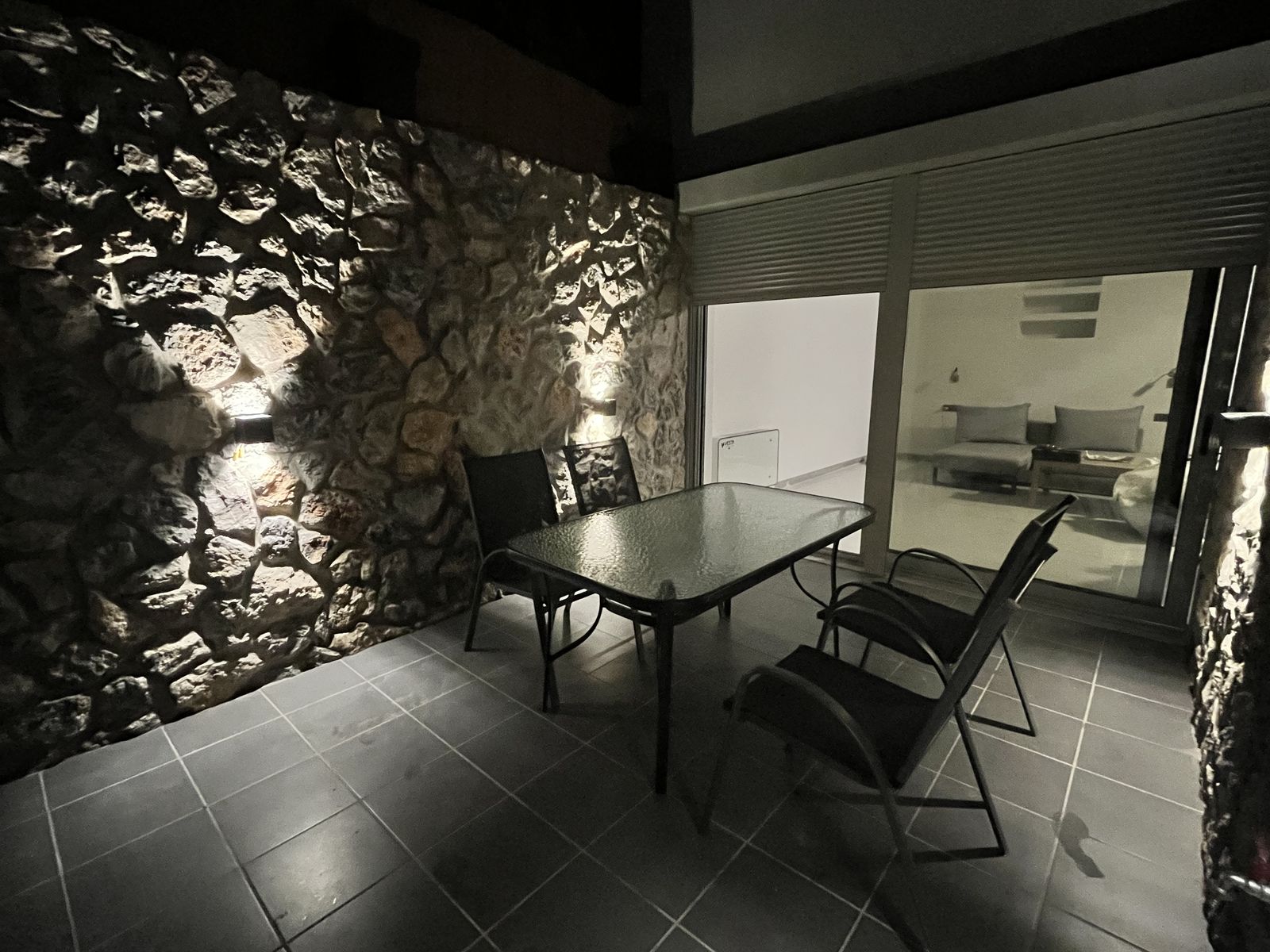 The sheltered stone courtyard, its dining table set outside the glass doors.