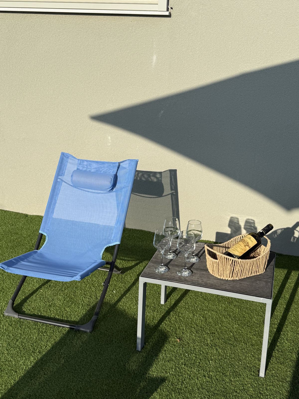 A lounger on the lawn with the welcome basket and glasses set out.