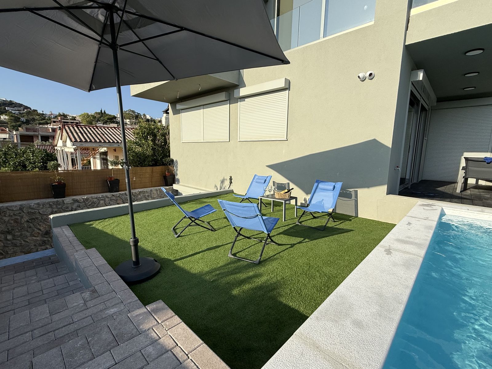 Sun loungers on the lawn at the pool's edge, under the umbrella.