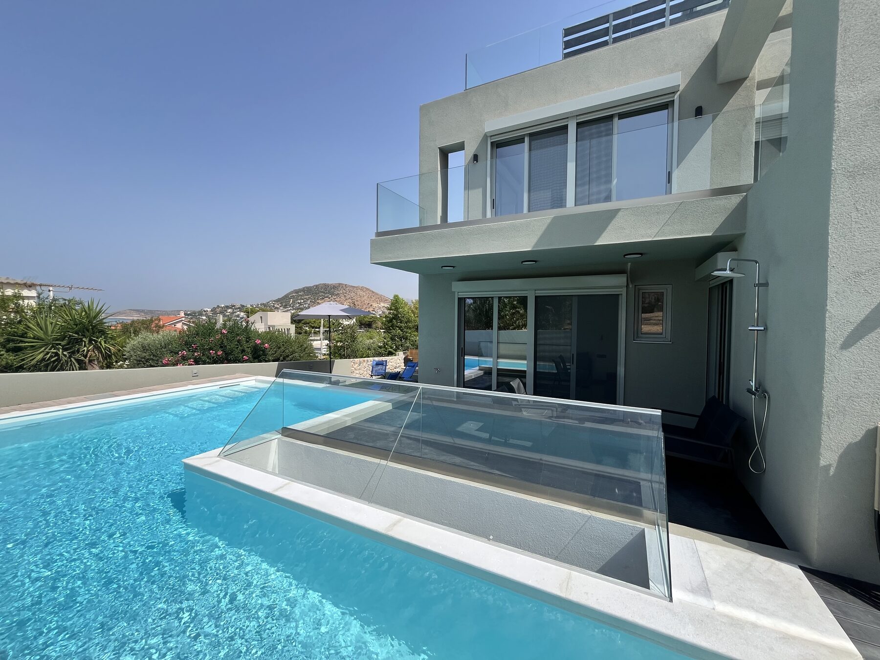 The pool running up to the villa, the glass-railed terraces of both apartments stacked above it.