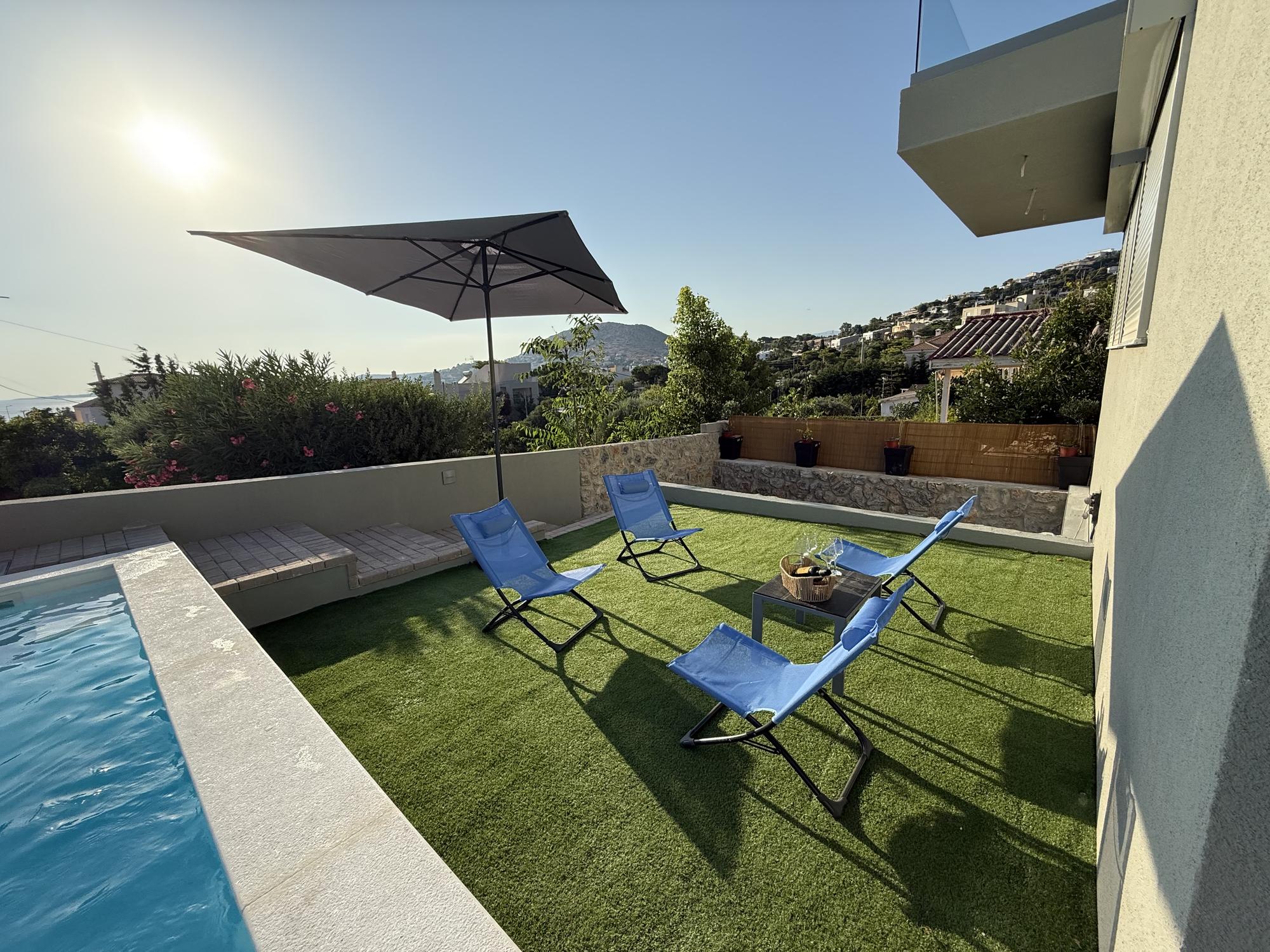 The lawn beside the shared pool at Blue Bay Dream B, with sun loungers under an umbrella.