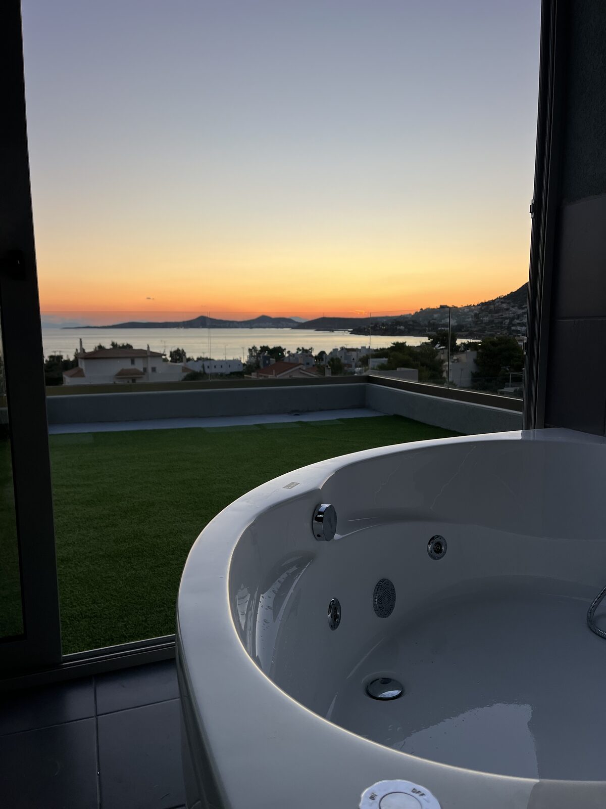 The rooftop jacuzzi looking out across the lawn to the gulf, the sun going down behind the headland.