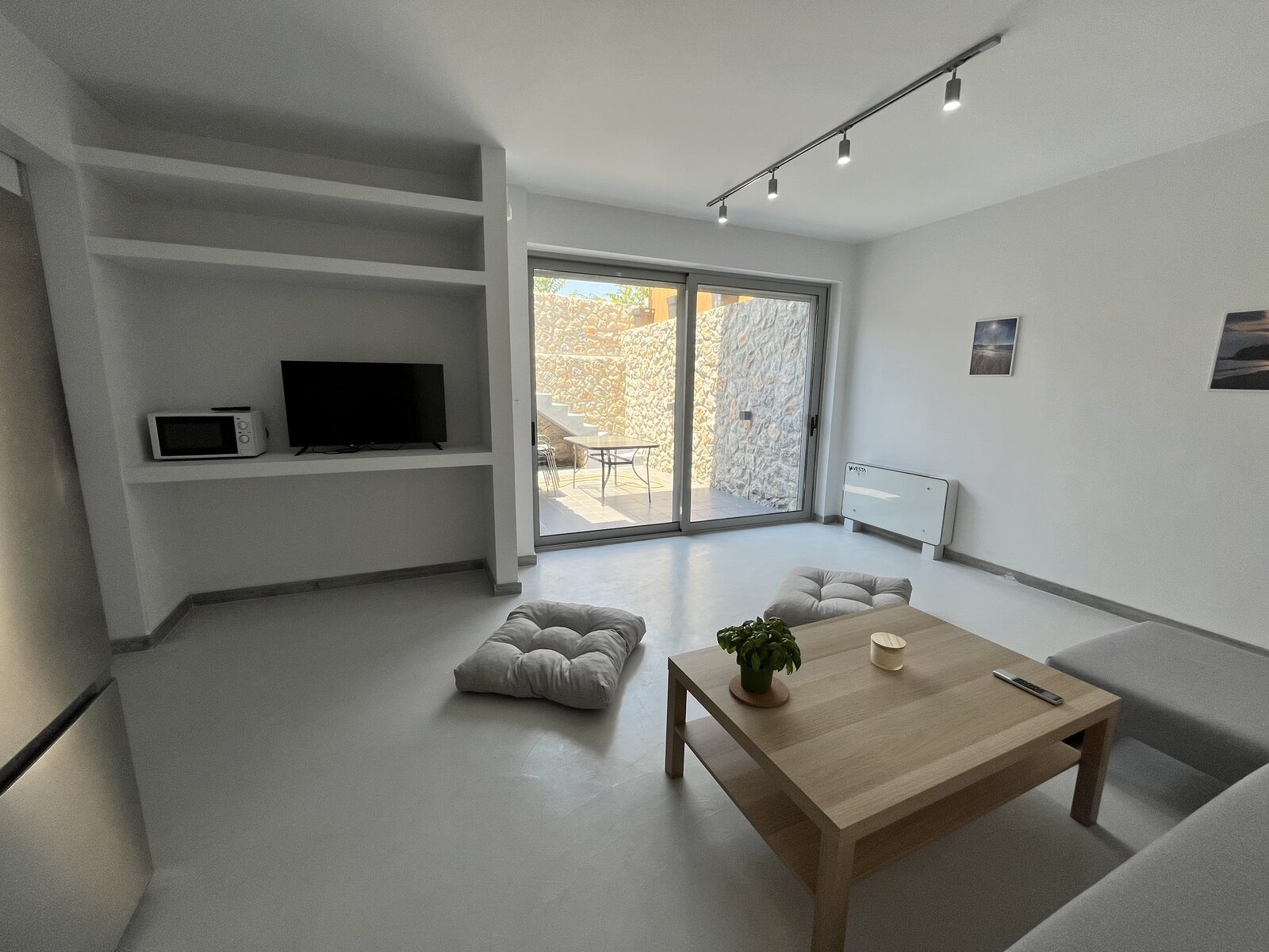 The garden-level living room — floor cushions and a low timber table, the courtyard through the glass.